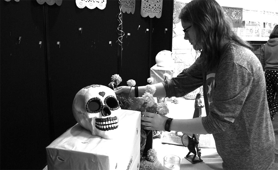 Maddy Kilmer, a sophomore majoring in creative writing, helps set up for Day of the Dead in the Falls Room of the University Center, where people honored their loved ones who have died.