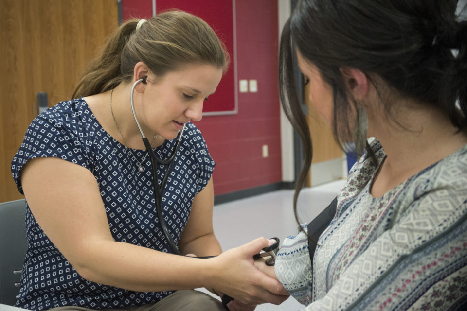 Clinical exercise physiology graduate student Emily Youngstrand, left, listens to the heartbeat of Hailey Skog in the Gary Thibodeau Health and Human Performance Laboratory during the Falcon Center grand opening Sept. 21, 2017.